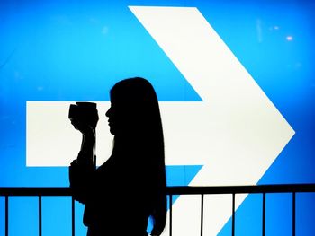 Young woman photographing against blue sky