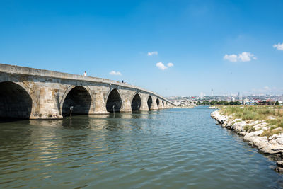 Arch bridge over river against blue sky