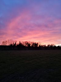 Silhouette trees on field against romantic sky at sunset