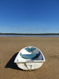 White boat on sand with clear blue sky