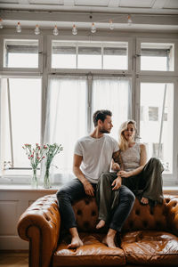 Friends sitting on sofa at home