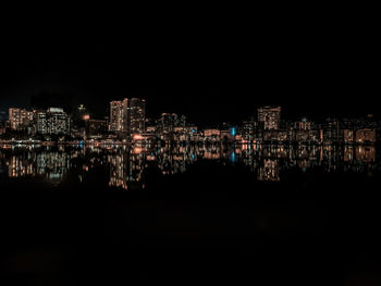 Illuminated buildings in city against clear sky at night