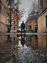 Reflection of man in puddle on building