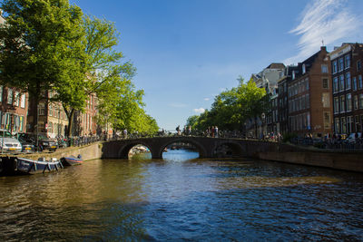 Bridge over river in city against sky