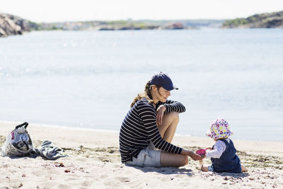 Mother playing with baby girl on beach