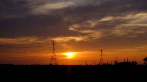 Silhouette electricity pylon against sky during sunset