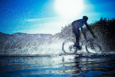 Man riding bicycle on stream against sky