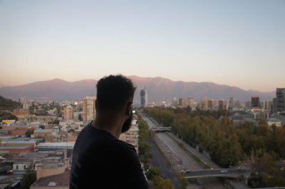 Rear view of man standing by buildings in city against sky