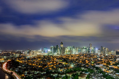 Illuminated cityscape against cloudy sky