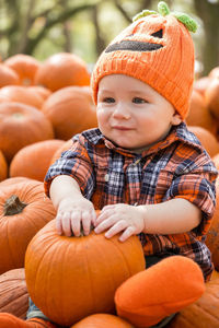 Close-up of baby boy looking away while sitting on pumpkins during halloween