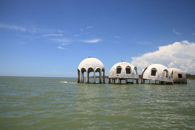 Gazebo in sea against blue sky