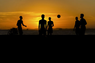 Young people playing beach soccer during sunset at ribeira beach in salvador, bahia, brazil.