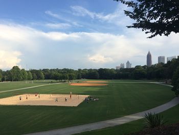 Scenic view of golf course against sky in city