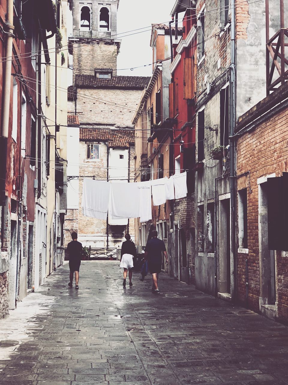 PEOPLE WALKING ON FOOTPATH AMIDST BUILDINGS