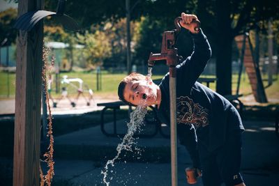 Boy drinking from water pump in park