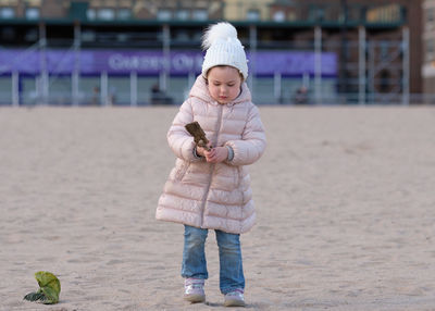 Little girl is playing on an empty beach on a cold day