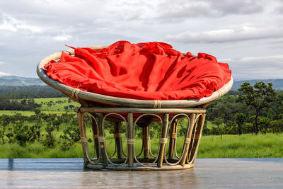 Chairs made of rattan and upholstery fabrics in red on wooden terrace .