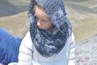 High angle view of girl looking away while sitting outdoors