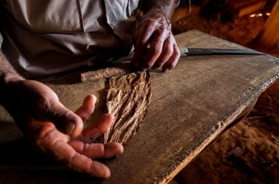 Midsection of man manufacturing tobacco