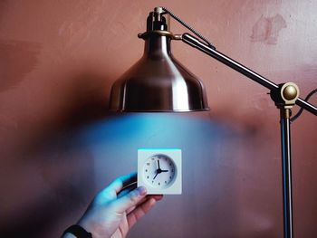 Close-up of cropped hand holding clock