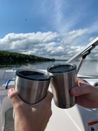 Midsection of person holding drink against sky