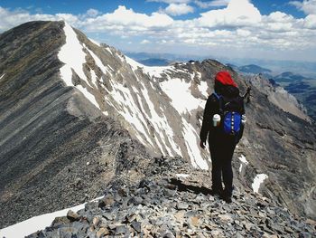 Rear view of man standing on rock against sky