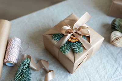 View of a christmas present beautifully wrapped and decorated with spruce branch and oranges slices.