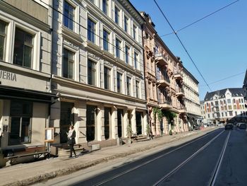 Man walking on road along buildings