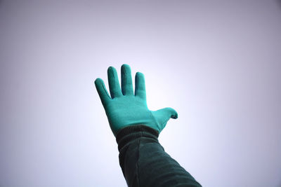 Low angle view of person wearing glove against clear sky during winter