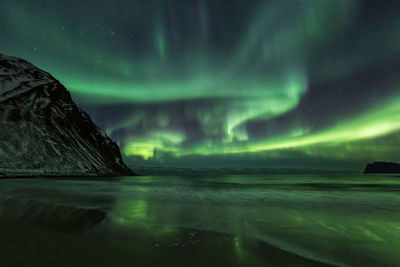 Scenic view of sea against aurora borealis at night