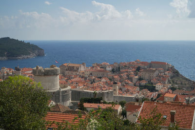 High angle view of town by sea against sky