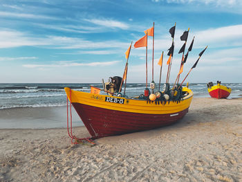 Deck chairs on beach against sky