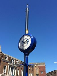 Low angle view of clock against clear blue sky