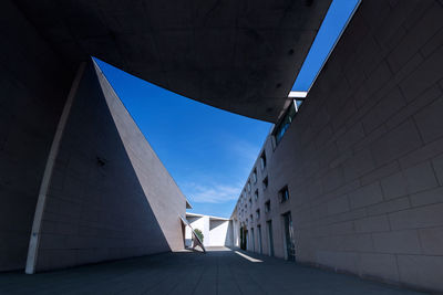 Low angle view of woman walking on building against blue sky