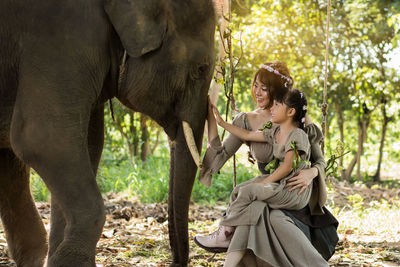 Mother and daughter touching elephant in forest