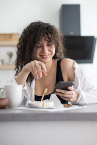 Portrait of woman using phone while sitting on table