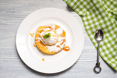 A ball of creamy vanilla ice cream on a slice of fried pineapple with caramel sauce. 