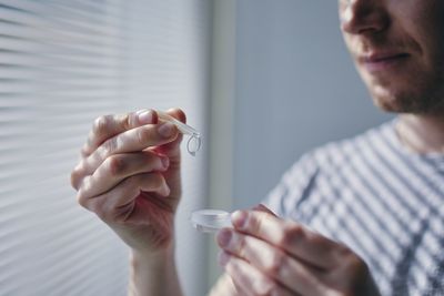 Midsection of man holding contact lens