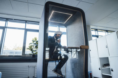 Businessman sitting in soundproof cabin at office