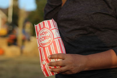 Midsection of man holding popcorn bag