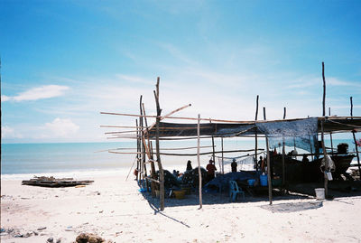 People under roof at beach against sky