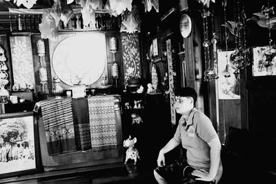 Side view of man sitting on illuminated ceiling