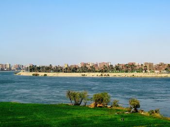 Scenic view of sea and buildings against clear sky