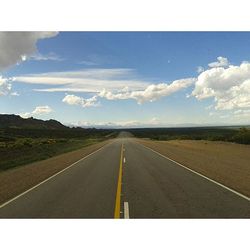 Empty road leading towards dramatic sky