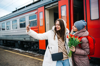 Girls with flowers on the station platform take a farewell selfie