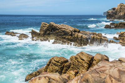 Rocks on shore by sea against sky