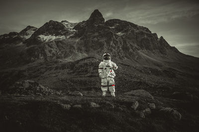 Man standing on rock with mountain range against sky