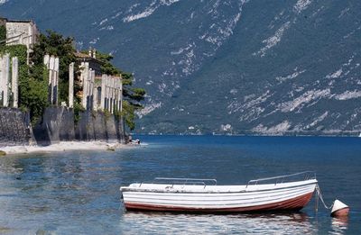 Boats moored on lake garda by mountain