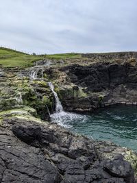 Scenic view of waterfall against sky