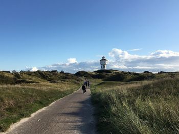 Rear view of people walking on road against sky